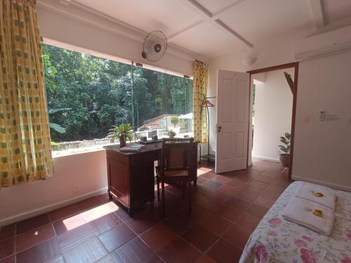 a bedroom with a desk and a large window at Casa São Conrado in Rio de Janeiro