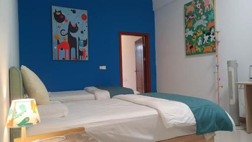 a blue room with two beds and a blue wall at 小红马民宿 in Yinzhan'ao