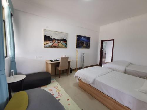 a bedroom with two beds and a desk and a table at 小红马民宿 in Yinzhan'ao