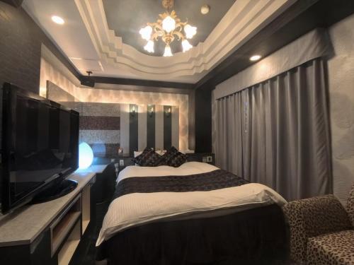 a bedroom with a bed and a flat screen tv at Hotel IRIS -アイリス- in Osaka