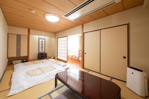 a bedroom with a large bed and a table at Yufuin Hotel Shuhokan in Yufuin