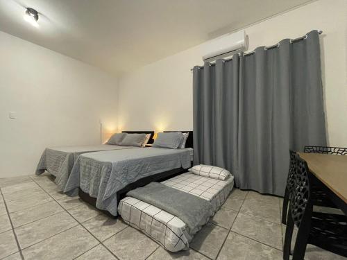 a bedroom with two beds and a table and a table at Villa Bilac - Amplos Studios 2km da Vila Germânica in Blumenau