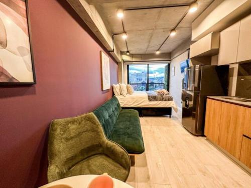 a living room with a green couch and a kitchen at Skyline Suites - Elegant Living with Coworking & Scenic Views in Bogotá