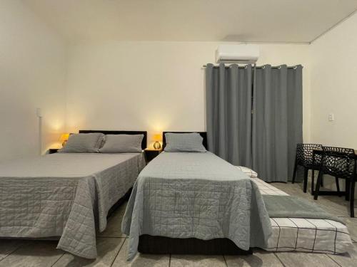 a bedroom with two beds and a window with curtains at Villa Bilac - Amplos Studios 2km da Vila Germânica in Blumenau