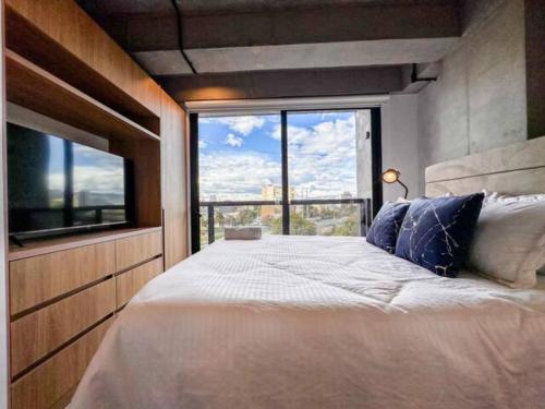 a bedroom with a large bed with a large window at Skyline Suites - Elegant Living with Coworking & Scenic Views in Bogotá