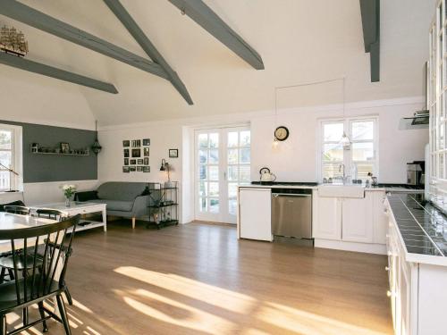 a kitchen and living room with white cabinets and a table at Idyllic Beach Retreat in Albaek in Ålbæk