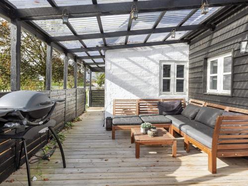a patio with a couch and a grill at Idyllic Beach Retreat in Albaek in Ålbæk