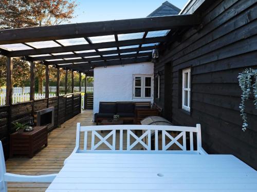 a patio with a white bench on a wooden deck at Idyllic Beach Retreat in Albaek in Ålbæk