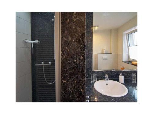 a bathroom with a sink and a shower with a mirror at Holiday apartment Kettenstek in Norddeich