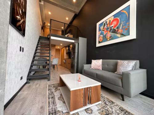 a living room with a couch and a staircase at Skyline Suites - Elegant Living with Coworking & Scenic Views in Bogotá