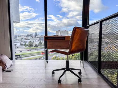 a chair sitting at a desk in front of a window at Skyline Suites - Elegant Living with Coworking & Scenic Views in Bogotá