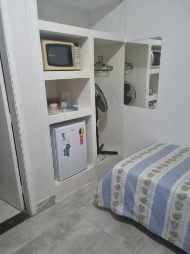 een slaapkamer met een bed, een magnetron en een televisie bij Quarto verde Asa Sul in Brasilia