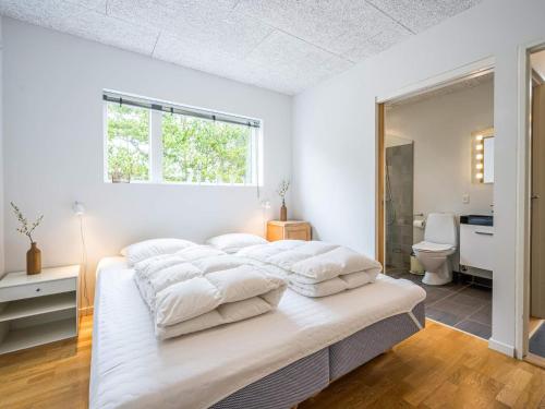 a white bedroom with a large bed with white sheets at 6 person holiday home in Henne in Henne Strand