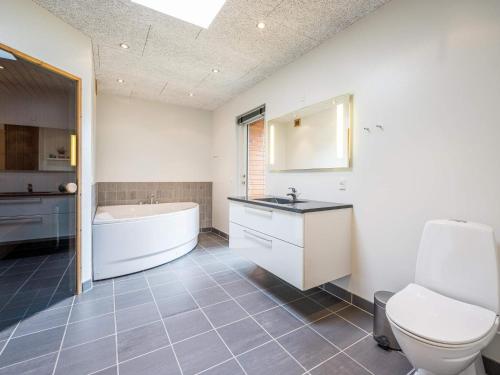 a bathroom with a tub and a toilet and a sink at 6 person holiday home in Henne in Henne Strand