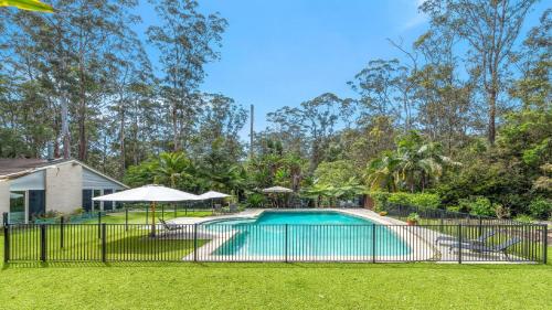 a swimming pool with an iron fence around a yard at 'Wirreanda Retreat - Acreage' by HolidayCo in Macmasters Beach