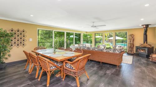 a dining room with a table and chairs and a couch at 'Wirreanda Retreat - Acreage' by HolidayCo in Macmasters Beach