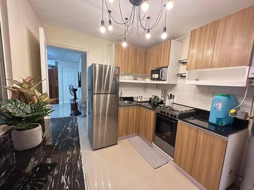 eine Küche mit Edelstahlkühlschrank und Holzschränken in der Unterkunft Betty's Midori in Antipolo