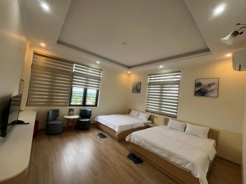 a bedroom with two beds and a tv and windows at Happy Home Dak Lak in Buôn Mhang