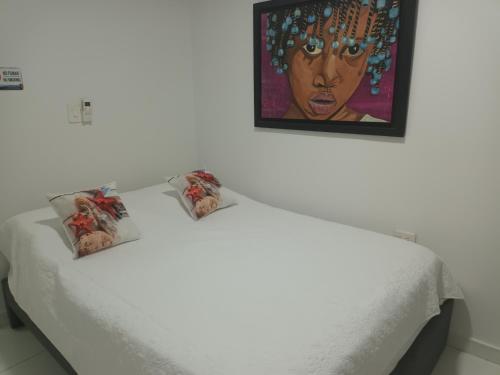 a white bed with a painting on the wall at Hospedaje Belleza Isleña habitaciones Individuales in San Andrés