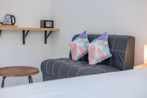 a black leather couch with two pillows on it at Karon Hotel at 22 in Karon Beach