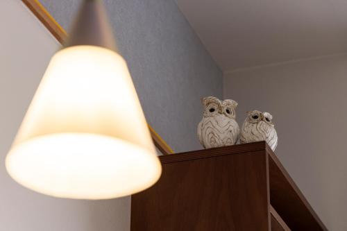 two white owls sitting on top of a shelf with a light at Tokyu Stay Ikebukuro in Tokyo