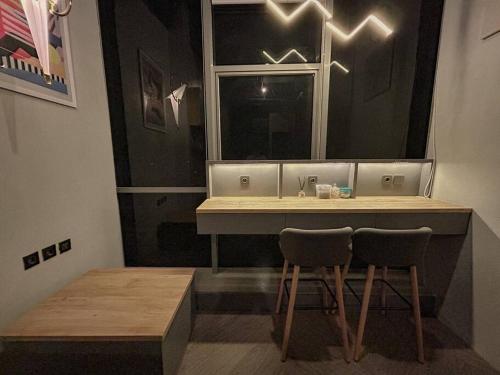 a kitchen with two chairs and a counter and a window at Comfy Loft at Fairview Apartment Karawaci in Tangerang