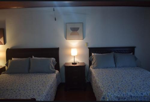 a bedroom with two beds and a lamp on a night stand at Acogedora y amplia habitación en La Tropicana in Alajuela City