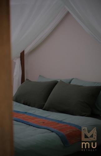 a bed in a bedroom with a white wall at MU Retreat in Vũ Lao