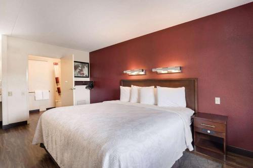 a bedroom with a large bed with a red wall at Super 8 by Wyndham Deerfield - Northbrook in Deerfield
