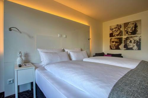 a bedroom with two white beds with posters on the wall at FourSide Plaza Hotel Trier, Trademark Collection by Wyndham in Trier