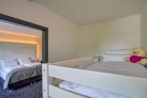 a teddy bear sitting on a bed in a bedroom at FourSide Plaza Hotel Trier, Trademark Collection by Wyndham in Trier