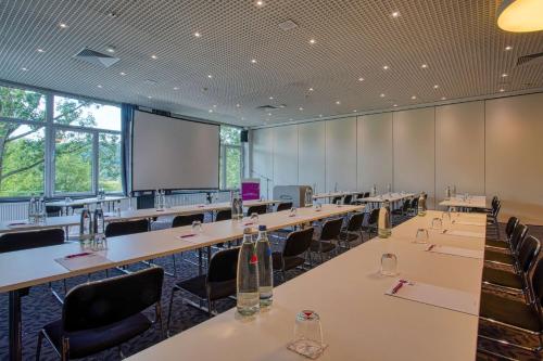 a conference room with tables and chairs and a screen at FourSide Plaza Hotel Trier, Trademark Collection by Wyndham in Trier