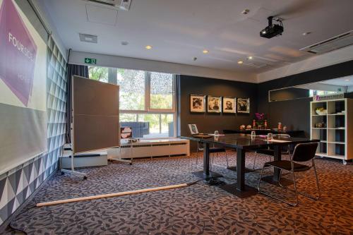 a meeting room with a table and a chalkboard and a screen at FourSide Plaza Hotel Trier, Trademark Collection by Wyndham in Trier