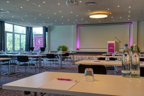 a conference room with tables and chairs and a projection screen at FourSide Plaza Hotel Trier, Trademark Collection by Wyndham in Trier