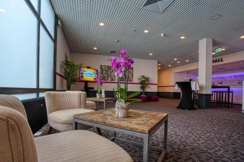 a lobby with chairs and a table with flowers on it at FourSide Plaza Hotel Trier, Trademark Collection by Wyndham in Trier