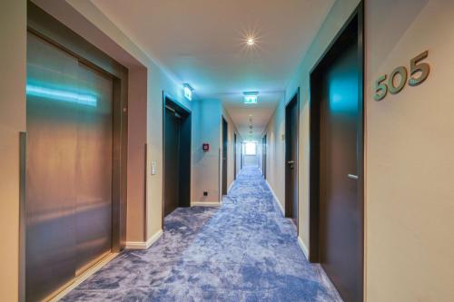 a corridor of an office with blue walls and doors at PLAZA INN Ulm in Ulm