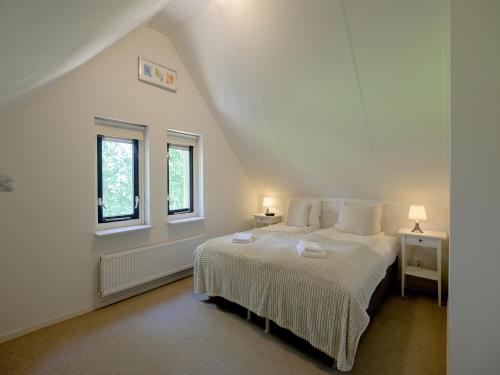 a white bedroom with a bed and two windows at Bungalow in Sondel near Slotermeer Lake in Sondel