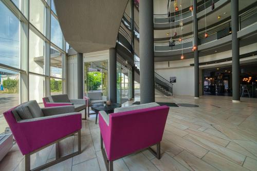 a lobby with purple chairs in a building at FourSide Hotel Salzburg Messe, Trademark Collection by Wyndham in Salzburg