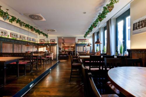 a restaurant with wooden tables and chairs and windows at Centro Hotel Stern Ulm City, Trademark Collection by Wyndham in Ulm