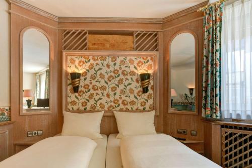 a bedroom with two beds and two mirrors at Centro Hotel Stern Ulm City, Trademark Collection by Wyndham in Ulm