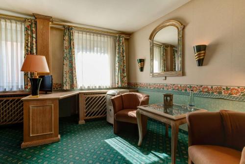 a hotel room with a desk and a mirror at Centro Hotel Stern Ulm City, Trademark Collection by Wyndham in Ulm