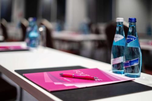a pink clipboard with a pen and two bottles of water at FourSide Hotel Salzburg Messe, Trademark Collection by Wyndham in Salzburg