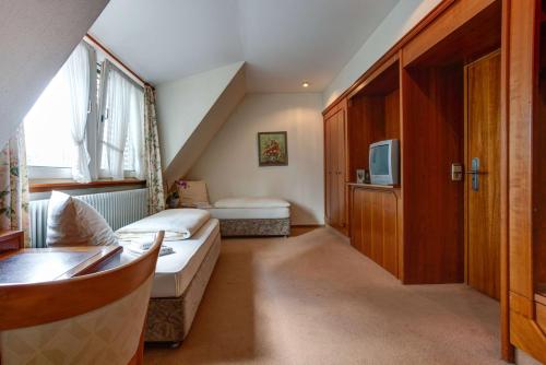 a small room with a bed and a tv at Centro Hotel Stern Ulm City, Trademark Collection by Wyndham in Ulm