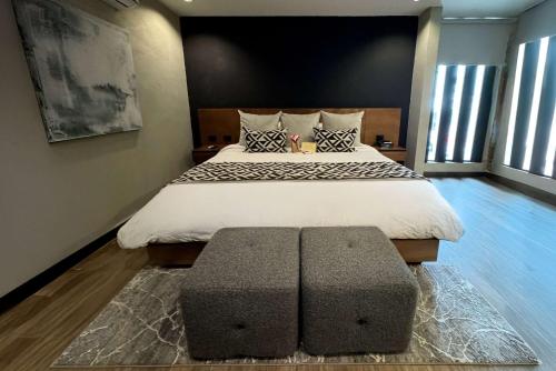 a bedroom with a large bed with a ottoman at Esplendor by Wyndham San Luis Potosi in San Luis Potosí