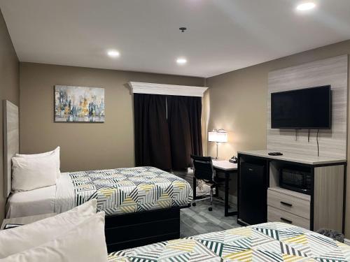 a hotel room with two beds and a desk and a television at Motel 6 Houma, LA in Houma