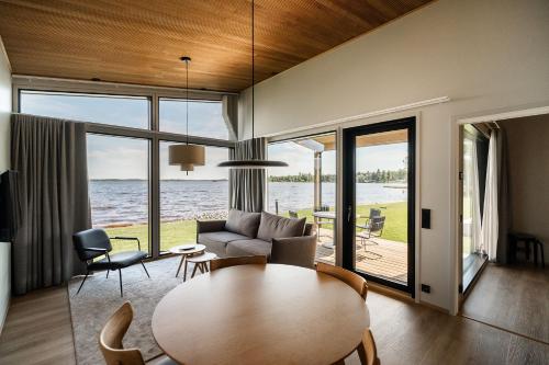 a living room with a table and a view of the water at Strandis Smokehouse Camping & Resort, Villas in Luoto