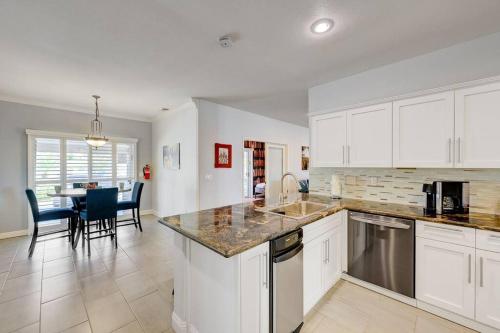 a kitchen with white cabinets and a table and chairs at Villa Del Sol in Henderson
