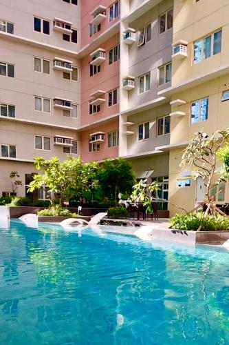 a swimming pool in front of a building at Matawhay Staycation at One Regis in Bacolod