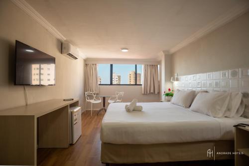 a bedroom with a large white bed and a desk at Rede Andrade Casa Blanca in Fortaleza