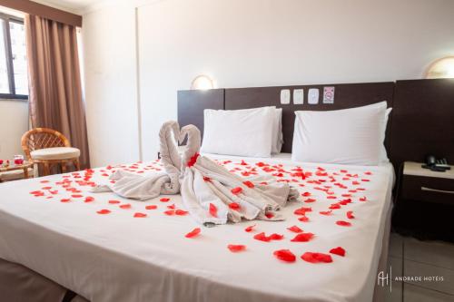 a bed with red rose petals on it at Rede Andrade Casa Blanca in Fortaleza